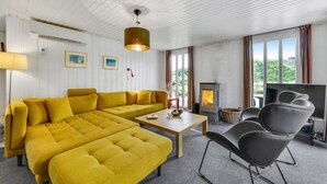 Ett modernt vardagsrum med en gul soffa, ett soffbord i trä, en öppen spis och en tv.