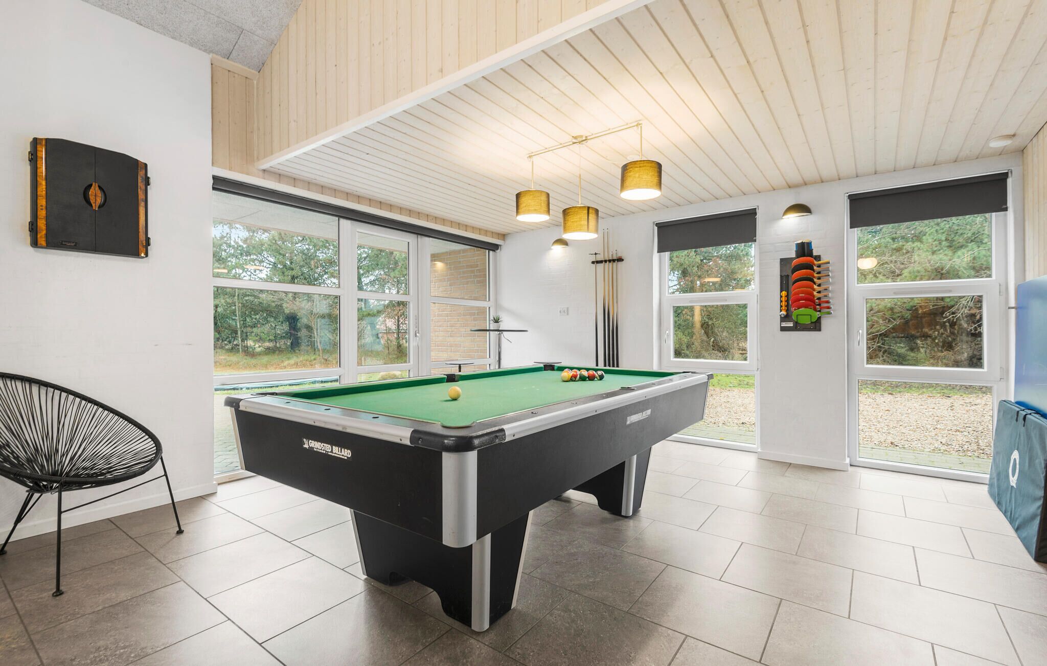 Une salle de billard équipée d’une table de billard, d’une chaise et d’un porte-billes.