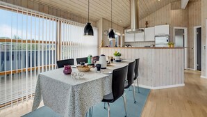 Una cocina moderna con armarios de madera, una isla central y una zona de comedor con mesa y sillas.