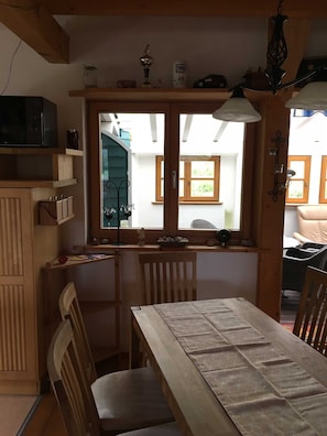 Un rincón comedor acogedor con una mesa y sillas de madera, una ventana con vistas al exterior y un estante con diversos objetos.