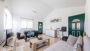 Een moderne woonkamer met een bank, een salontafel, een televisie en een tafelvoetbaltafel.