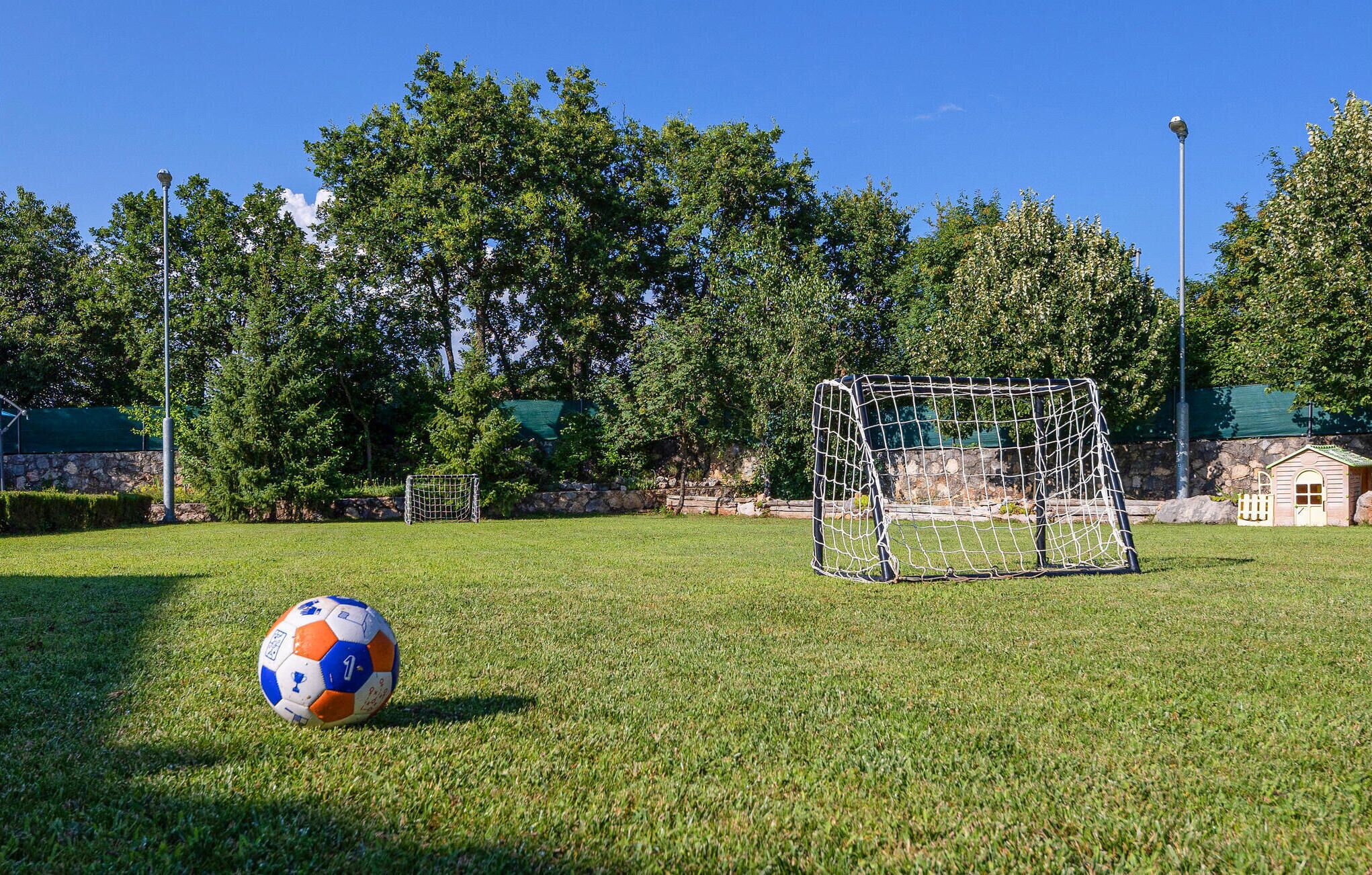 A soccer goal on a grassy field with trees in the background.