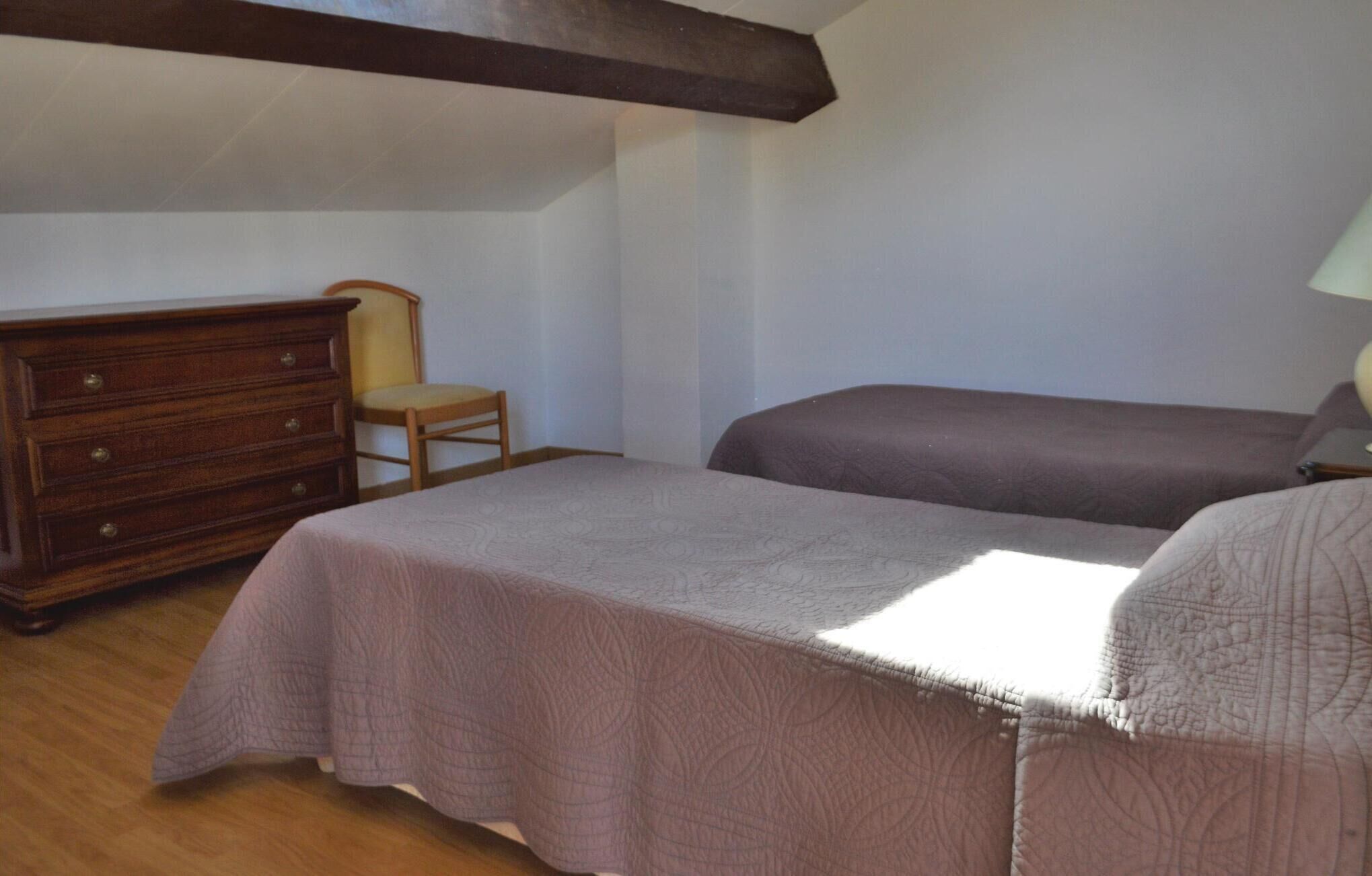 Un dormitorio con una cama, un aparador y una silla.