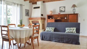 Ein gemütliches Wohnzimmer mit Kamin, Holzmöbeln und einer Essecke mit Tisch für zwei Personen.
