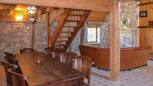 A rustic dining area with a wooden table and chairs, a stone wall, and a wooden staircase. - Cozy home in Padirac/Bascoul with WiFi (Padirac/Bascoul)