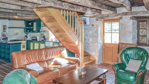 A cozy living room with a brown leather sofa, a green armchair, and a wooden coffee table. A wooden staircase leads to an upper level. - Cozy home in Padirac/Bascoul with WiFi (Padirac/Bascoul)