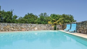 A swimming pool with a stone wall and palm tree, surrounded by greenery. - Cozy home in Padirac/Bascoul with WiFi (Padirac/Bascoul)