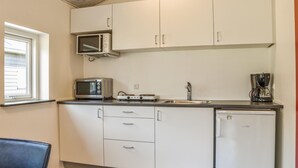 A compact kitchen with white cabinets, a microwave, a toaster, a coffee maker, and a dishwasher.