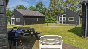 A wooden deck with a barbecue grill and a white plastic chair.