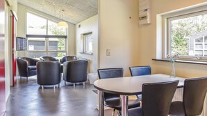 A conference room with a round table and six chairs, large windows, and a ceiling with exposed beams.