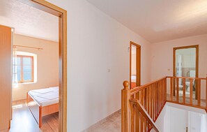 Une pièce avec un lit, une fenêtre, un miroir et un escalier.