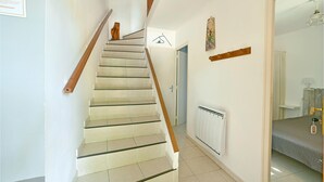 A staircase with wooden handrails and beige tiles, leading to a room with a radiator and a bed. - 3 bedroom nice home in Mazan (Mazan)