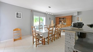A dining area with a table and chairs, a kitchen area with a stove and cabinets, and a view of the outdoors through a window. - 3 bedroom nice home in Mazan (Mazan)