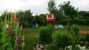 A garden with a small treehouse, a tent, and a pond. - Apartment 1 - family-friendly apartments in Recknitztal (Semlow)