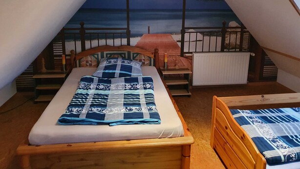 A triangular room with a bed, a small table, and a view of the sea. - Apartment 1 - family-friendly apartments in Recknitztal (Semlow)