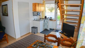A compact kitchen with a microwave, sink, and kettle. There is a dining area with a table and chairs. - Apartment 1 - family-friendly apartments in Recknitztal (Semlow)