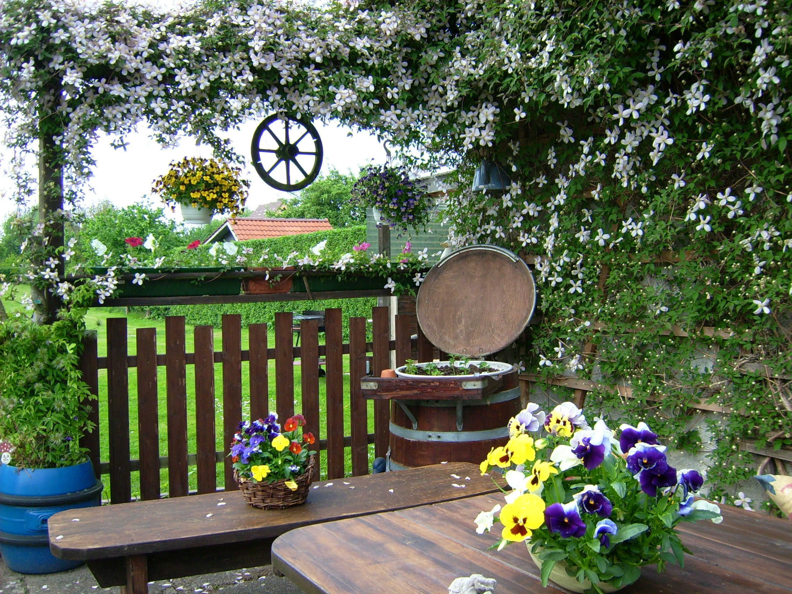 A wooden bench with a potted plant and a wooden barrel.