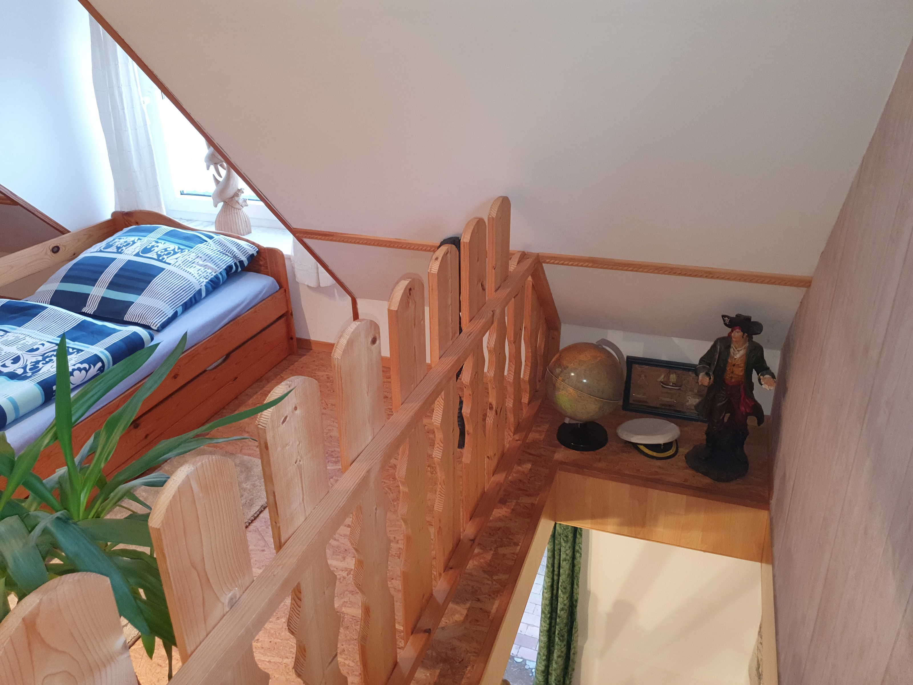 Ein Schlafzimmer mit einem hölzernen Bett, einem Globus, einer Figur und einem Fenster mit Vorhängen.