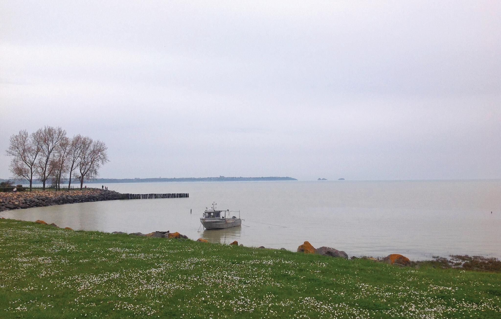 A calm lake with a small boat anchored near a rocky shore.