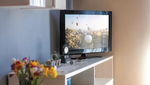A flat-screen TV on a white stand, displaying a scene with hot air balloons.