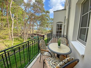A balcony with a round table and chairs, a view of trees and a building in the background. - House Meeresblick A 1.21 Beach oasis with balcony - F: House Meeresblick A 1.21 (Baabe)