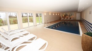 Una piscina con sillas de descanso, un mural y vistas al exterior.