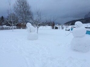 A snowy landscape with two snowmen and a clear sky.