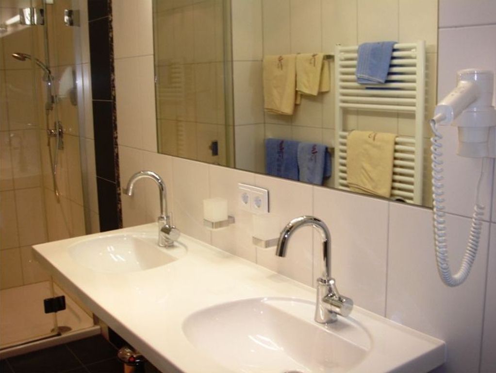 A bathroom with two sinks, a mirror, a towel rack, and a hairdryer.
