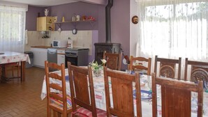 Een gezellige keuken met een houtkachel, houten stoelen en een eettafel gedekt voor vier personen.