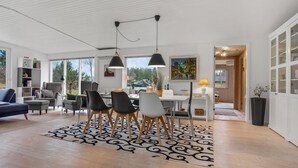 Un vaste espace de vie comprenant une table à manger, des chaises et une grande fenêtre donnant sur l’extérieur.
