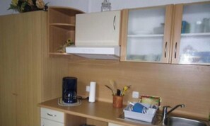 A kitchen with wooden cabinets, a coffee maker, and a sink. - Apartment - Private room - P. Krol (Erfurt)