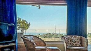 Ein Zimmer mit Korbmöbeln, einem Fernseher und Blick auf den Strand.