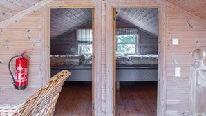 Eine Holzhütte mit zwei Schlafzimmern, jedes mit Fenster und Bett. Ein Feuerlöscher ist an der Wand angebracht.