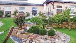 Een tuin met een vijver, een pad van stenen en een huis met zonnepanelen.