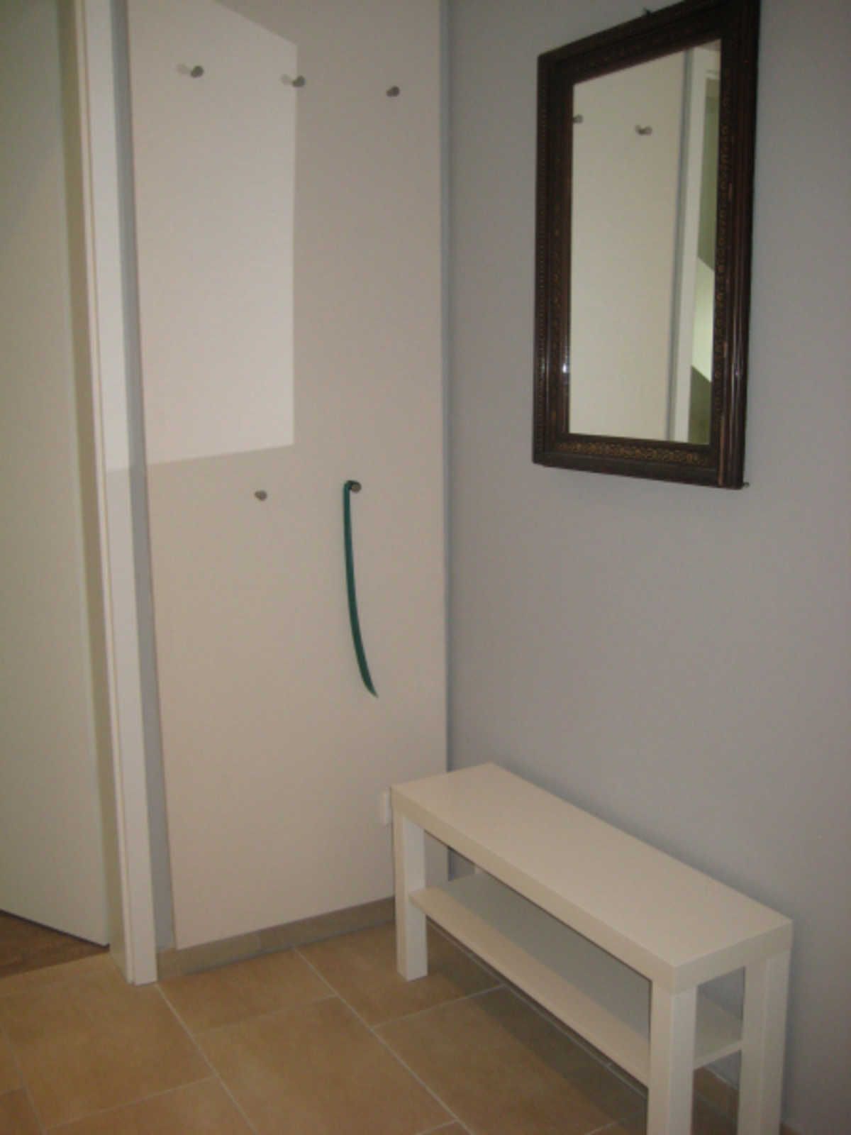 Kylpyhuone, jossa on valkoinen penkki, peili ja pyyheteline.