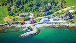 An aerial view of a coastal village with houses, a dock, and clear waters.