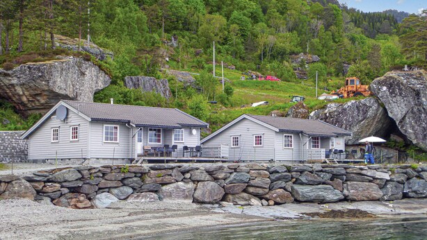 A coastal house with a stone wall and a view of the sea.