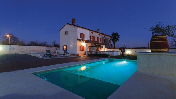 Area piscina con una casa, posti a sedere all'aperto e una grande botte decorativa.