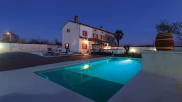 Area piscina con una casa, posti a sedere all'aperto e una grande botte decorativa.