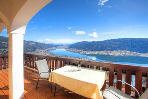 Ein Balkon mit Tisch und Stühlen mit Blick auf einen See und Berge.