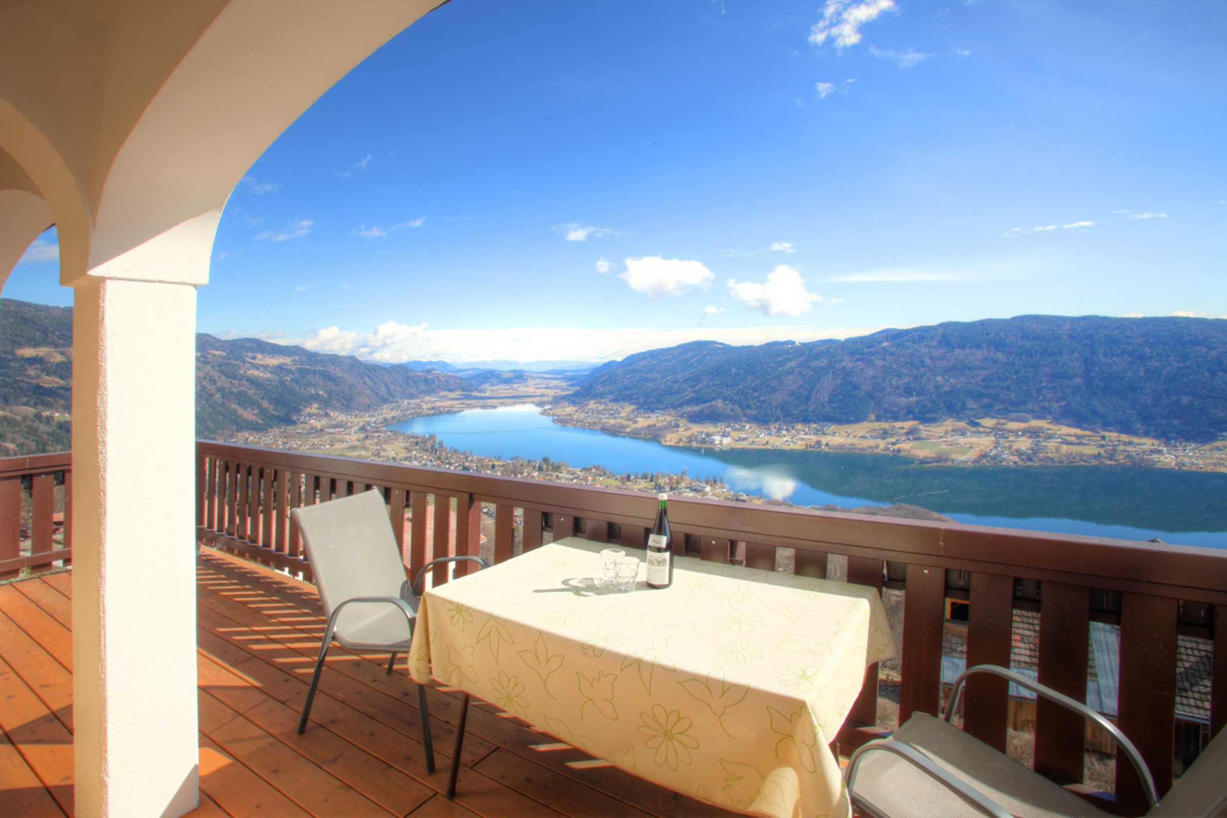 A balcony with a table, chairs, and a bottle of wine.