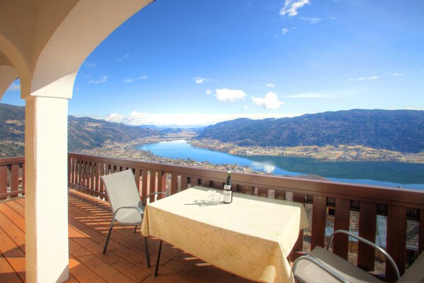 A balcony with a table, chairs, and a bottle of wine. - Mathiasl Panorama Apartments - Panorama Apartment (Winkl Ossiachberg)