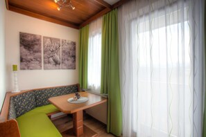 A room with a bench, a table, and three paintings on the wall. - Mathiasl Panorama Apartments - Panorama Apartment (Winkl Ossiachberg)