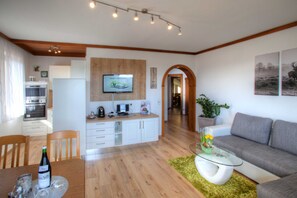 Un salon moderne avec un canapé, une table basse en verre et un coin repas comprenant une table et des chaises.