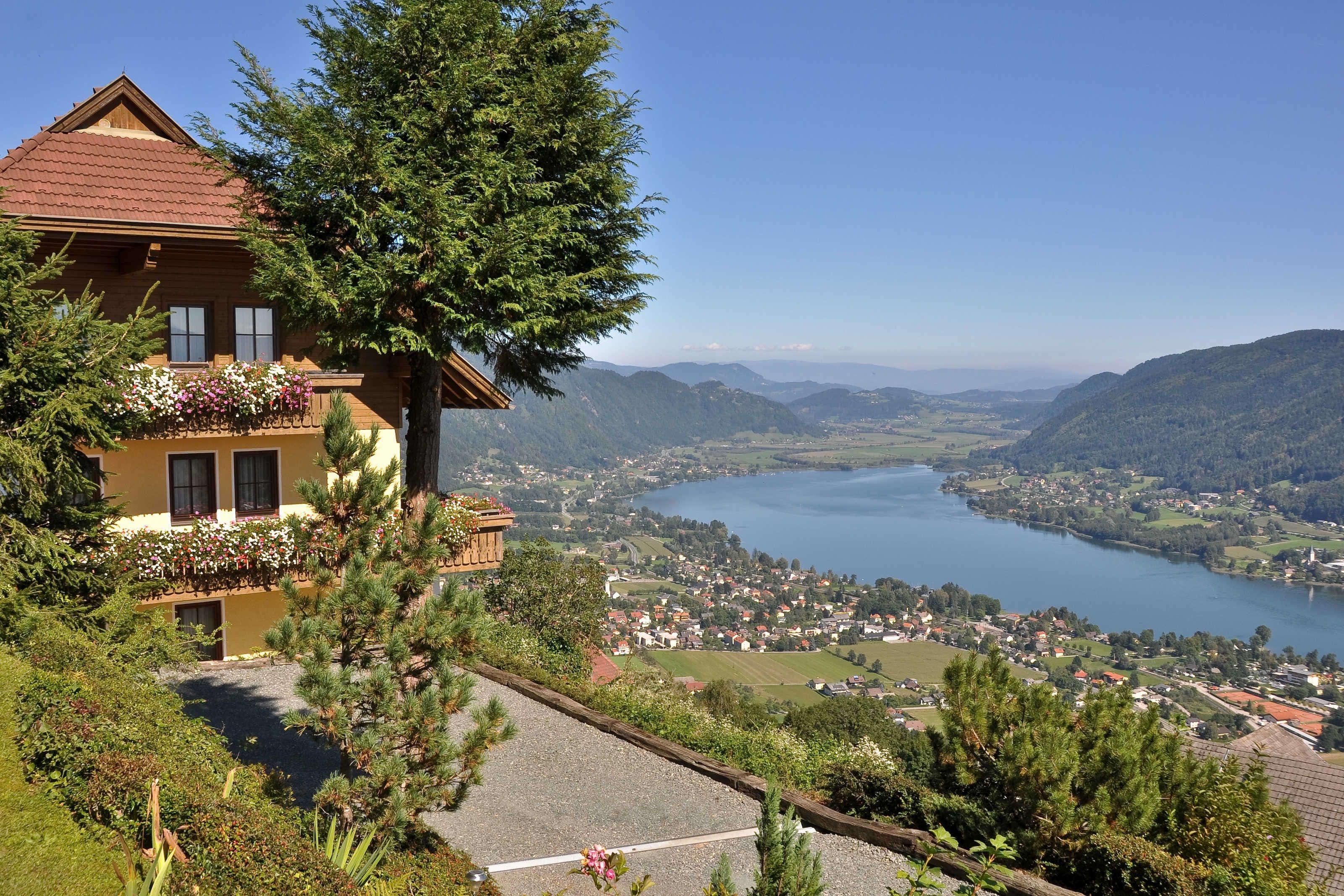 A chalet with a balcony overlooking a lake and mountains.
