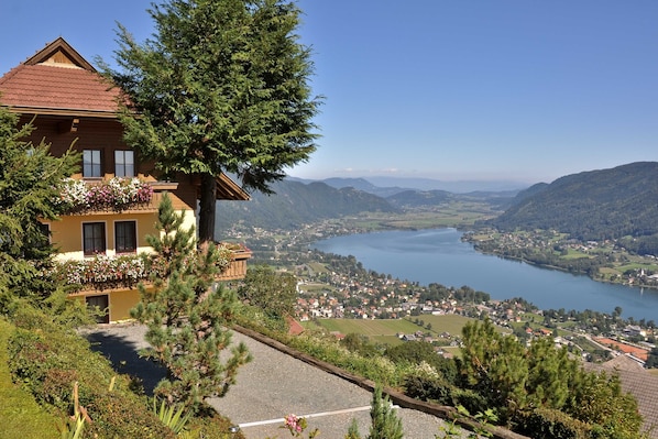 A chalet with a balcony overlooking a lake and mountains. - Mathiasl Panorama Apartments - Panorama Apartment (Winkl Ossiachberg)