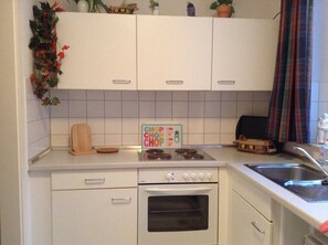 A compact kitchen with white cabinets, a stove, an oven, and a sink.