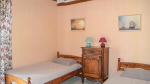 Un dormitorio con dos camas individuales, un aparador de madera y dos lámparas de pared.