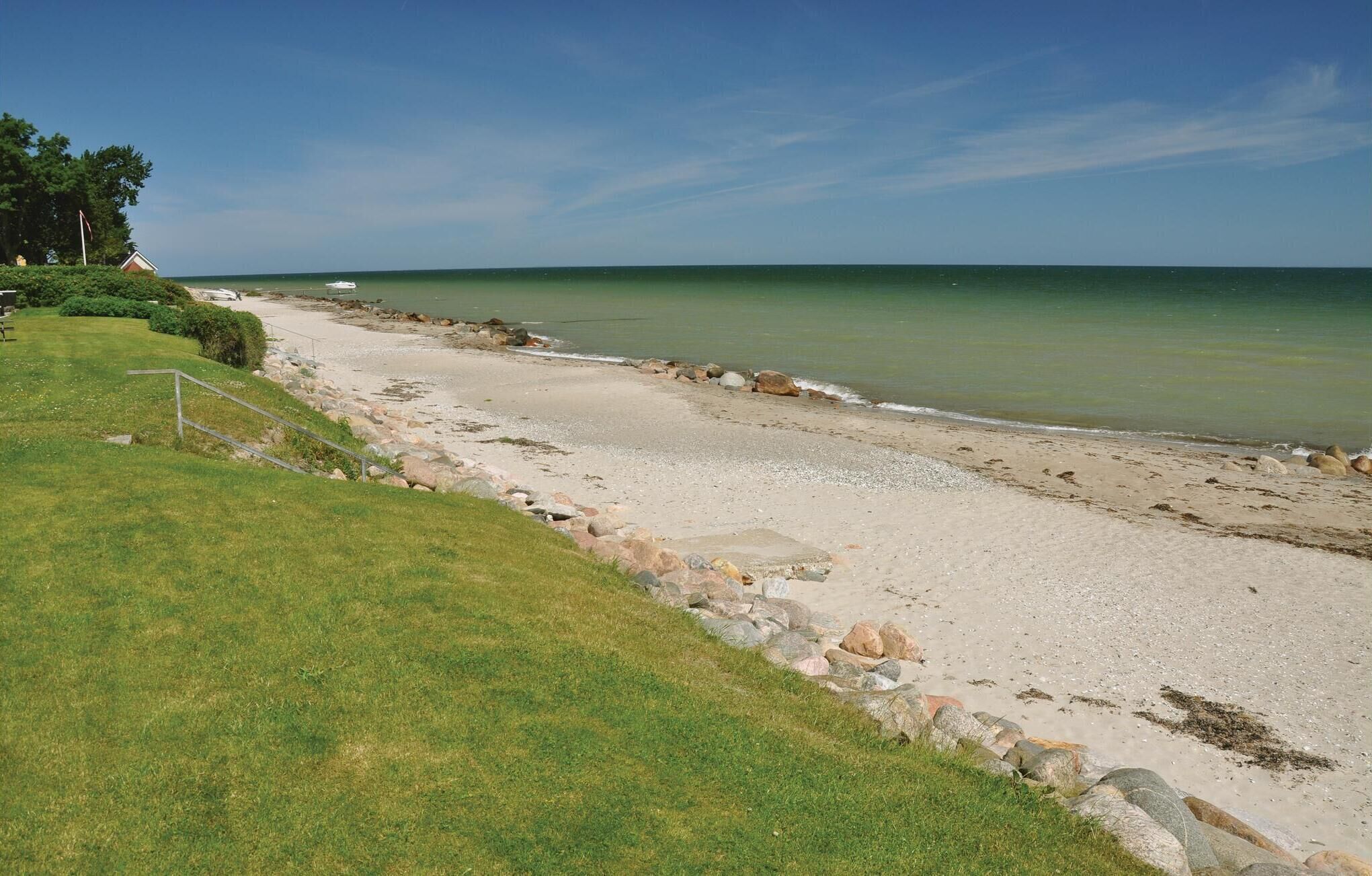 Une plage avec une zone herbeuse et une côte rocheuse.