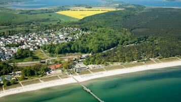 Luftaufnahme einer Küstenstadt mit Strand, Steg und umliegender Vegetation.